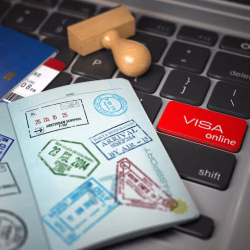 visa-online-application-concept-open-passport-with-visa-stamps-with-airline-boarding-pass-tickets-stamper-computer-keyboard_708636-1023
